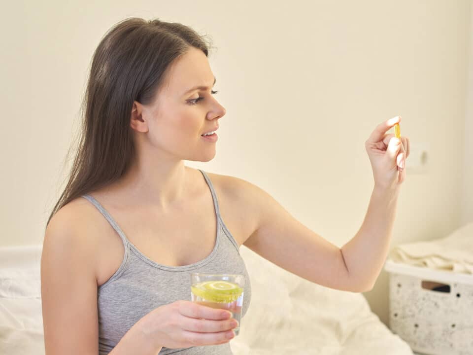 Mulher grávida tomando seu suplemento de ômega 3.